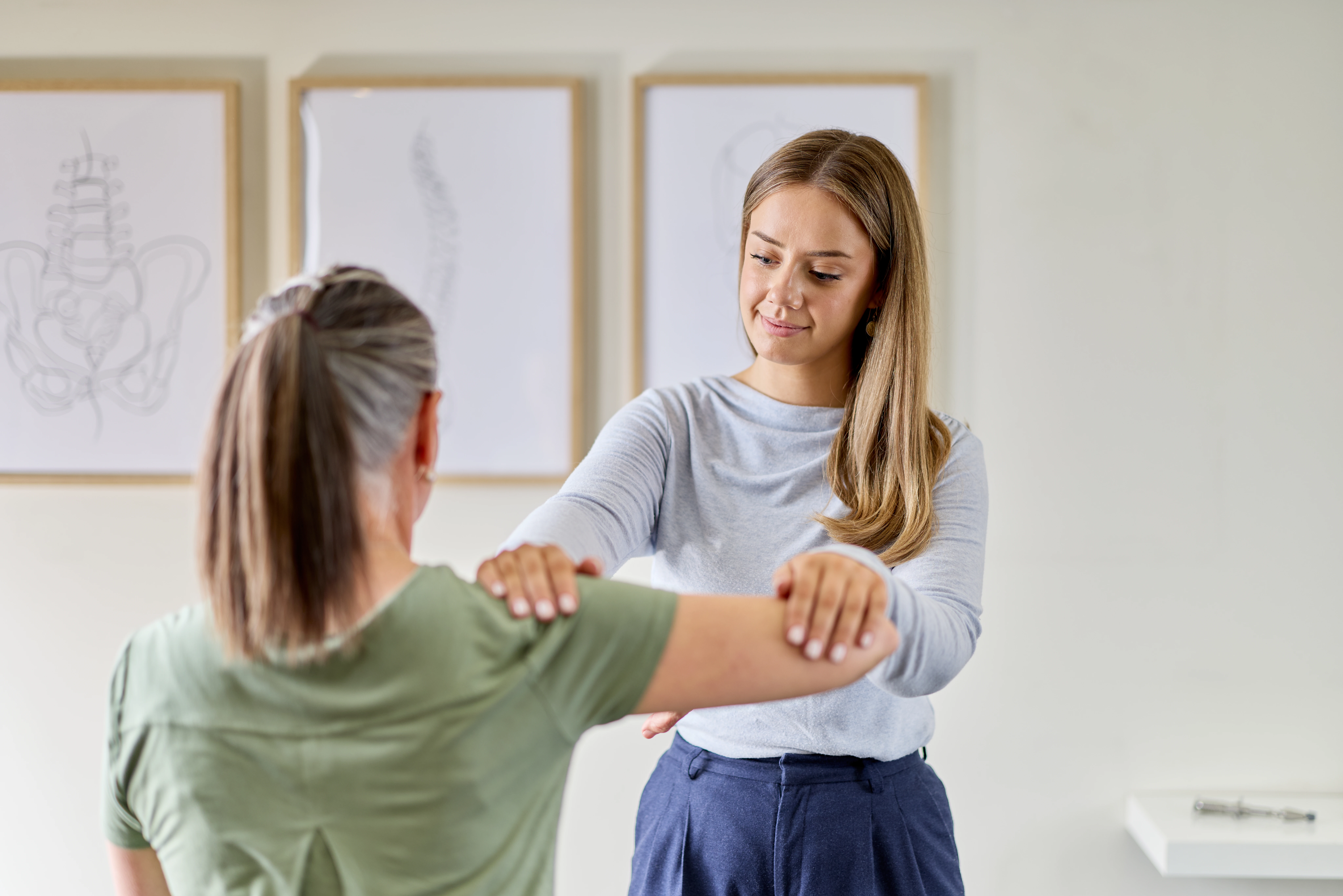 Dr Taylor Upton, chiropractor giving a female patient a seated shoulder treatment at Chiropractic Solutions Norwood Adelaide