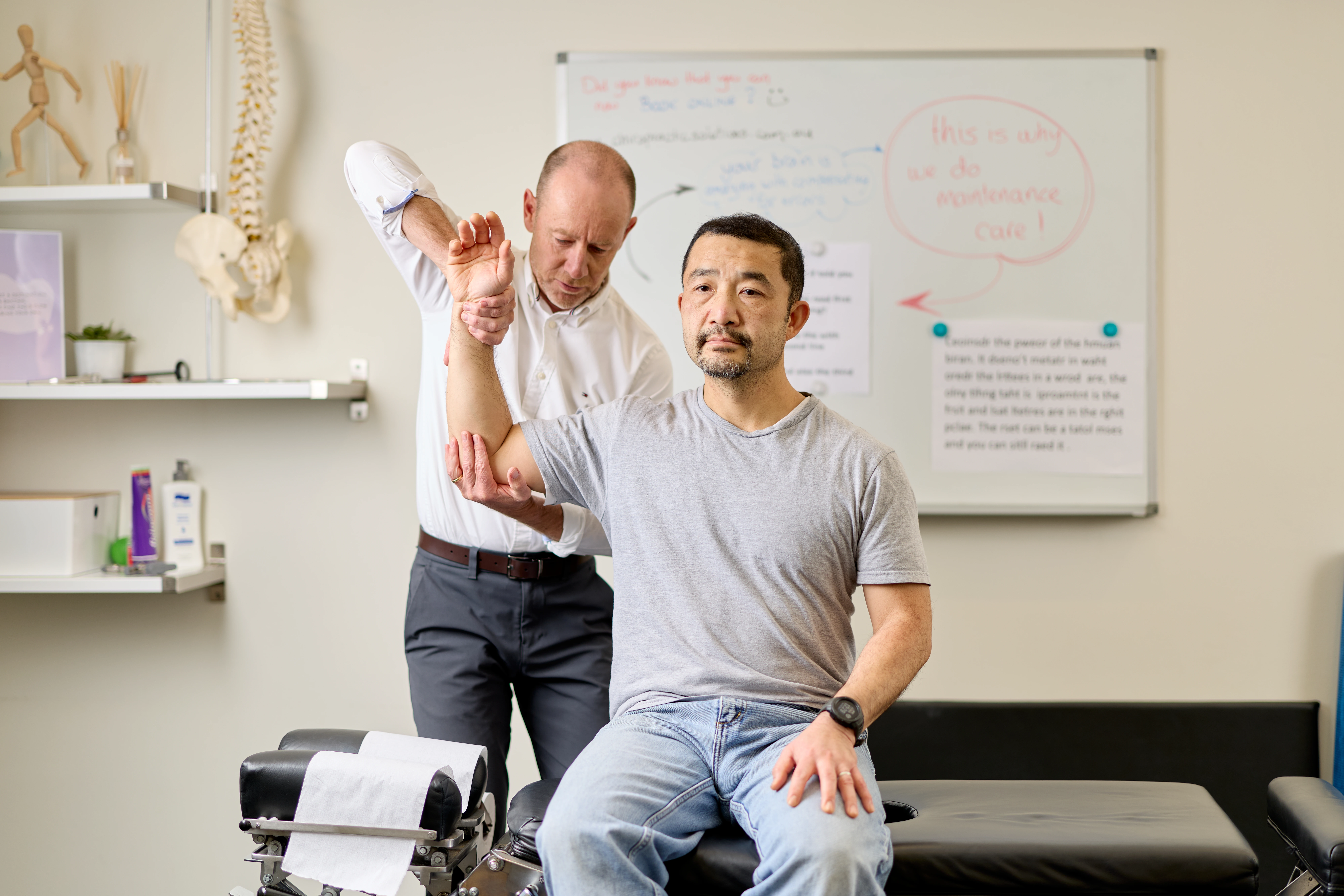 Dr Ken Leembruggen, chiropractor performing a shoulder muscle test on a male patient at Chiropractic Solutions Norwood Adelaide