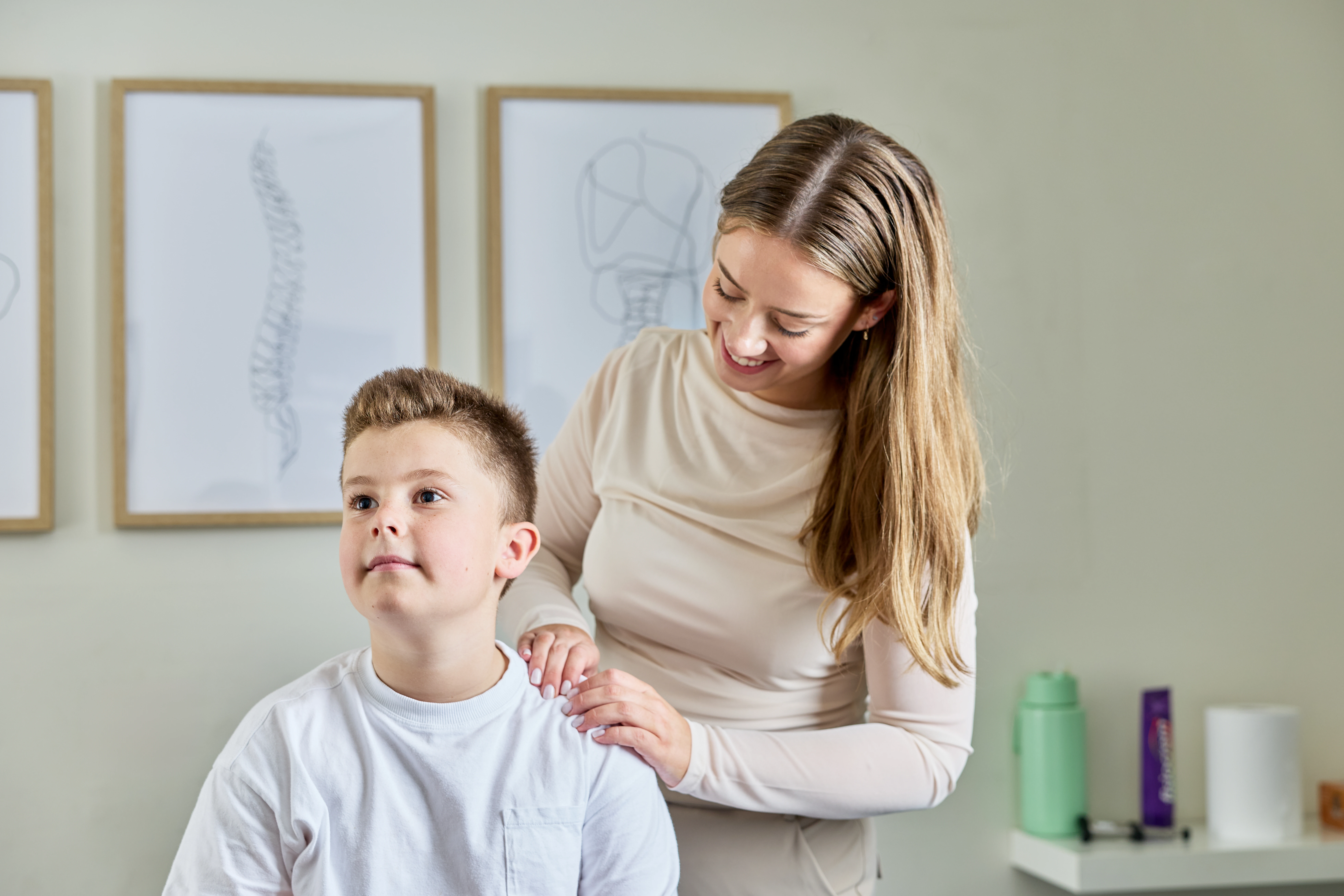A young boy having his shoulder checked by Dr Taylor Upton, a female chiropractor at Norwood Adelaide
