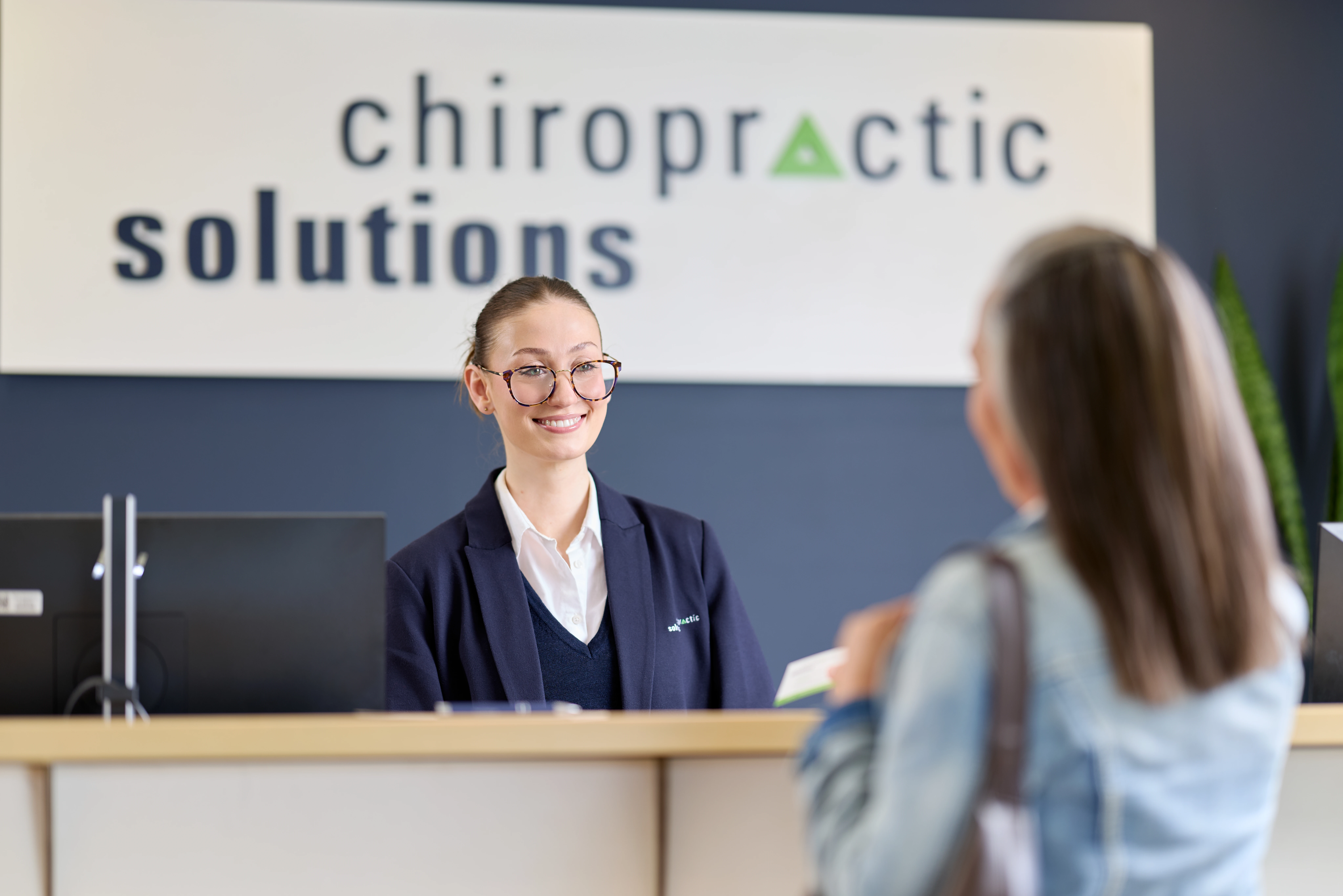 Receptionist serving a female patient at reception at Chiropractic Solutions Norwood Adelaide