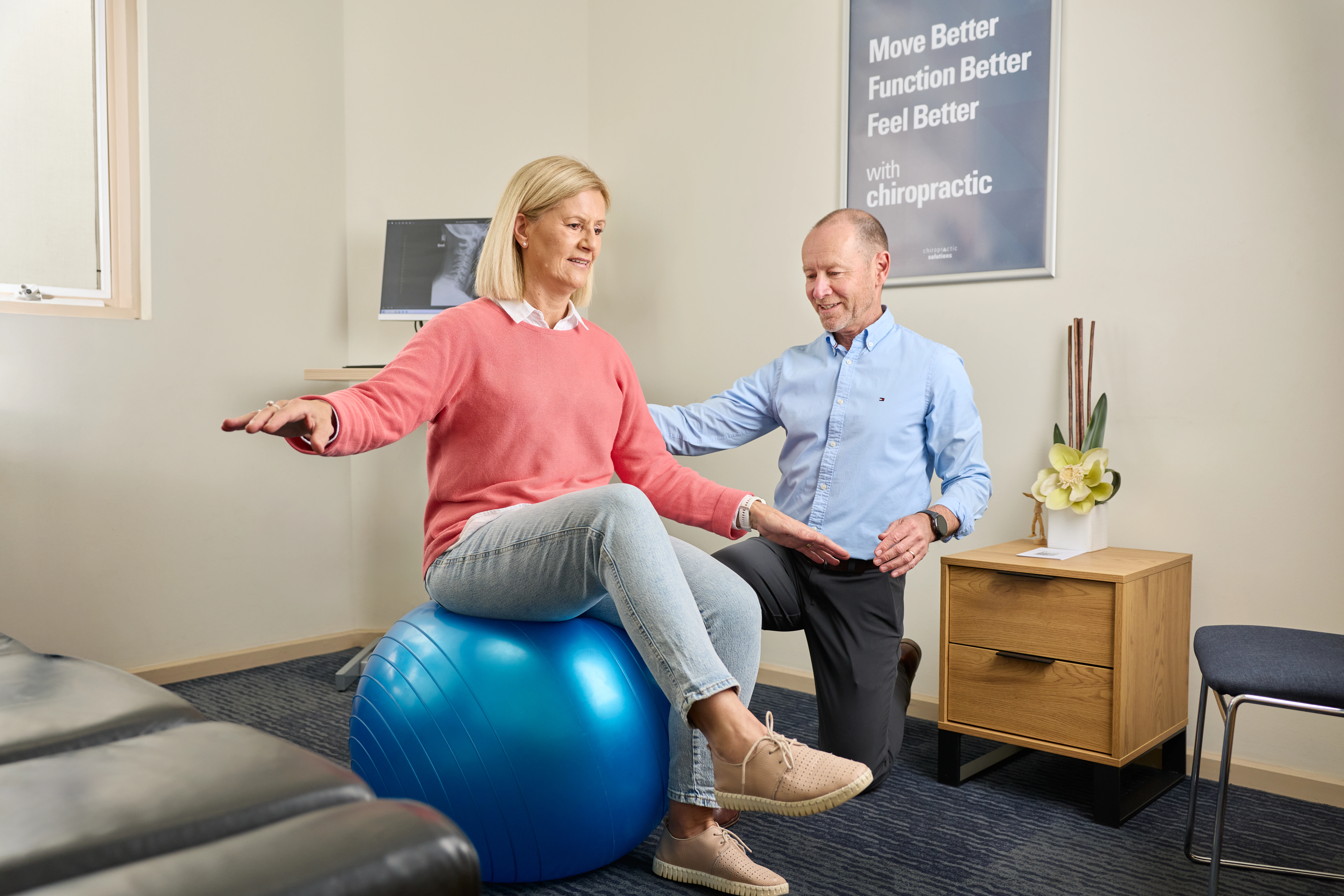 A female patient balancing on a fitball being assessed by Dr Ken Leembruggen, chiropractor at Norwood Adelaide