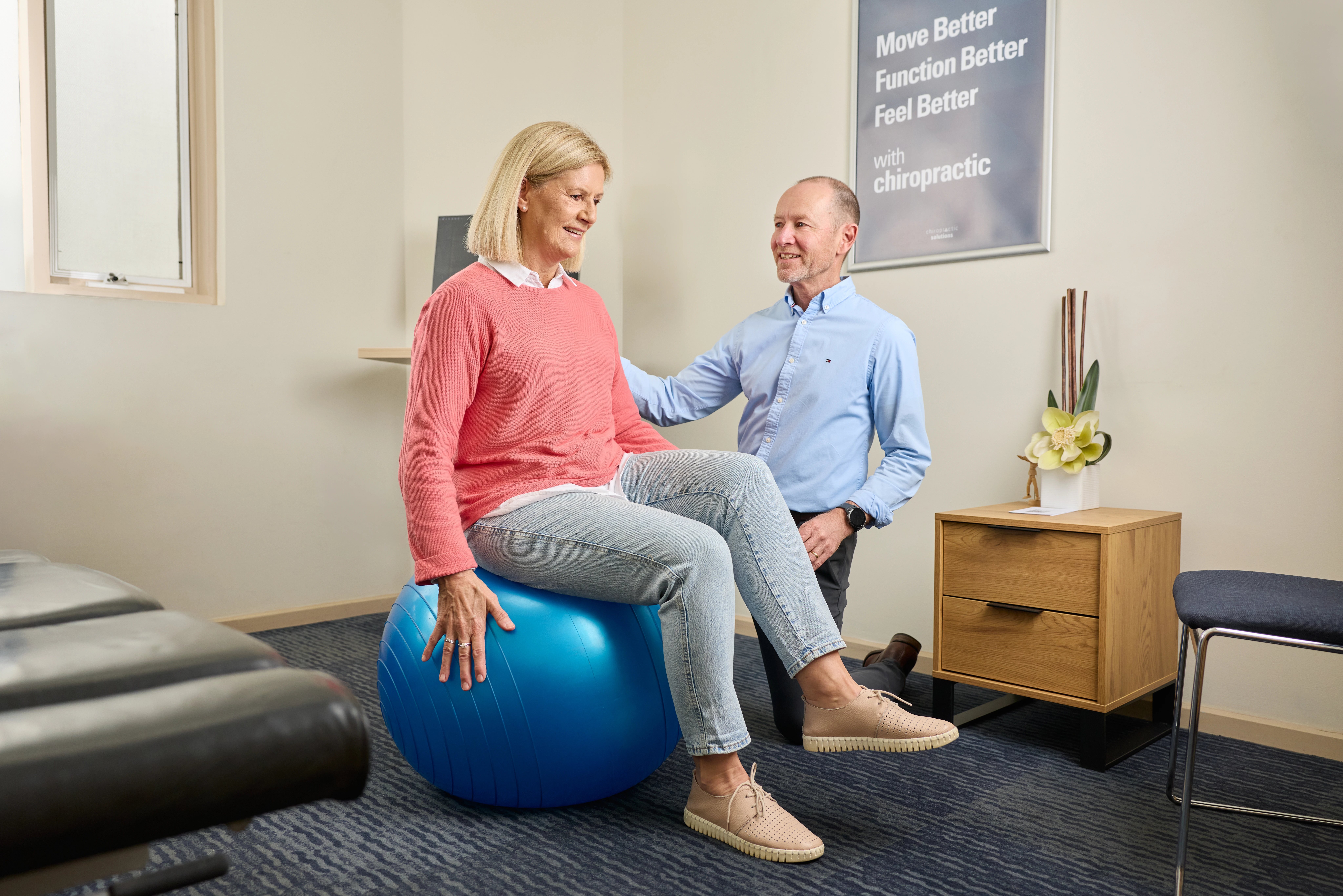 Dr Ken Leembruggen, chiropractor assisting a female patient with exercise ball at Chiropractic Solutions Norwood Adelaide