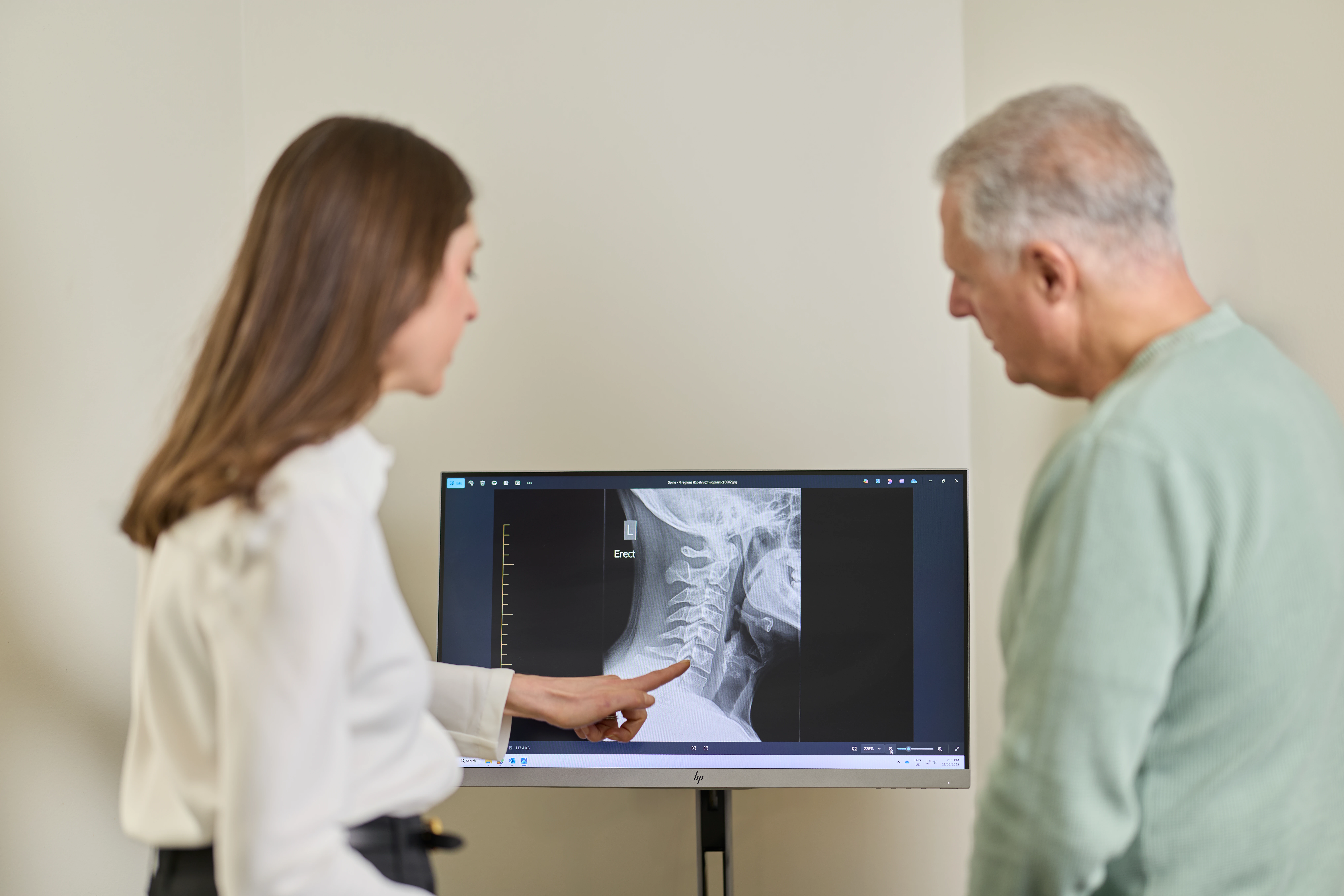 Dr Kimberley Manz, chiropractor pointing to xrays with a male patient at Chiropractic Solutions Norwood Adelaide